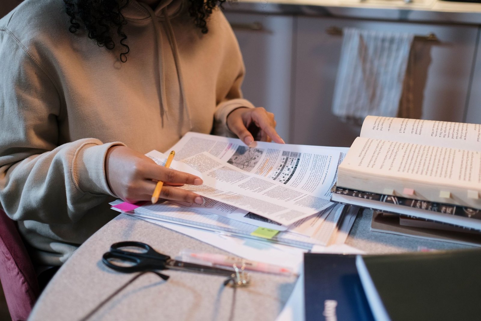 Close-up of a student marking up practice test papers and textbooks